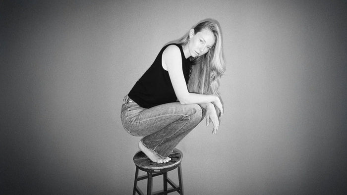 A woman sitting on a table wearing a denim skirt.